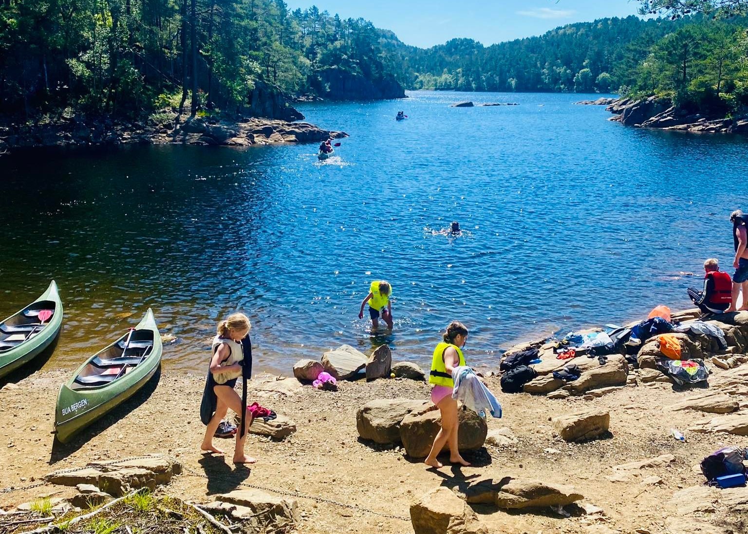 Tre bar som padler hver sin kajakk. Blå himmel og sommer